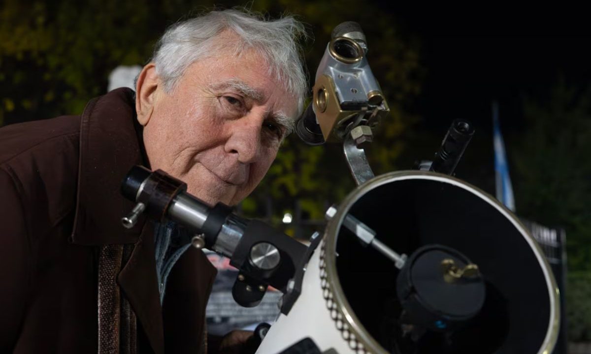 Idoso posa ao lado de telescópio artesanal construído com peças recicladas na Argentina.