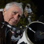 Idoso posa ao lado de telescópio artesanal construído com peças recicladas na Argentina.