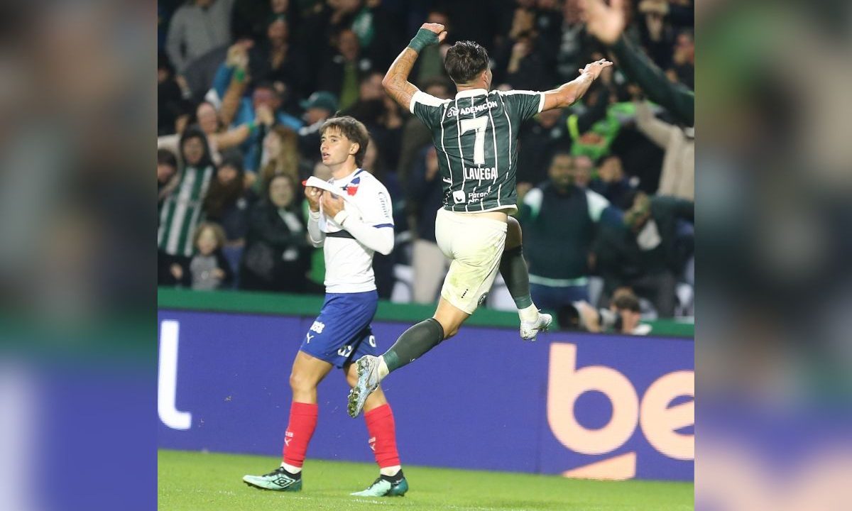 Joaquín Lavega salta e comemora pelo Coritiba no Couto Pereira, enquanto um jogador do Bahia aparece ao fundo durante partida do Campeonato Brasileiro.