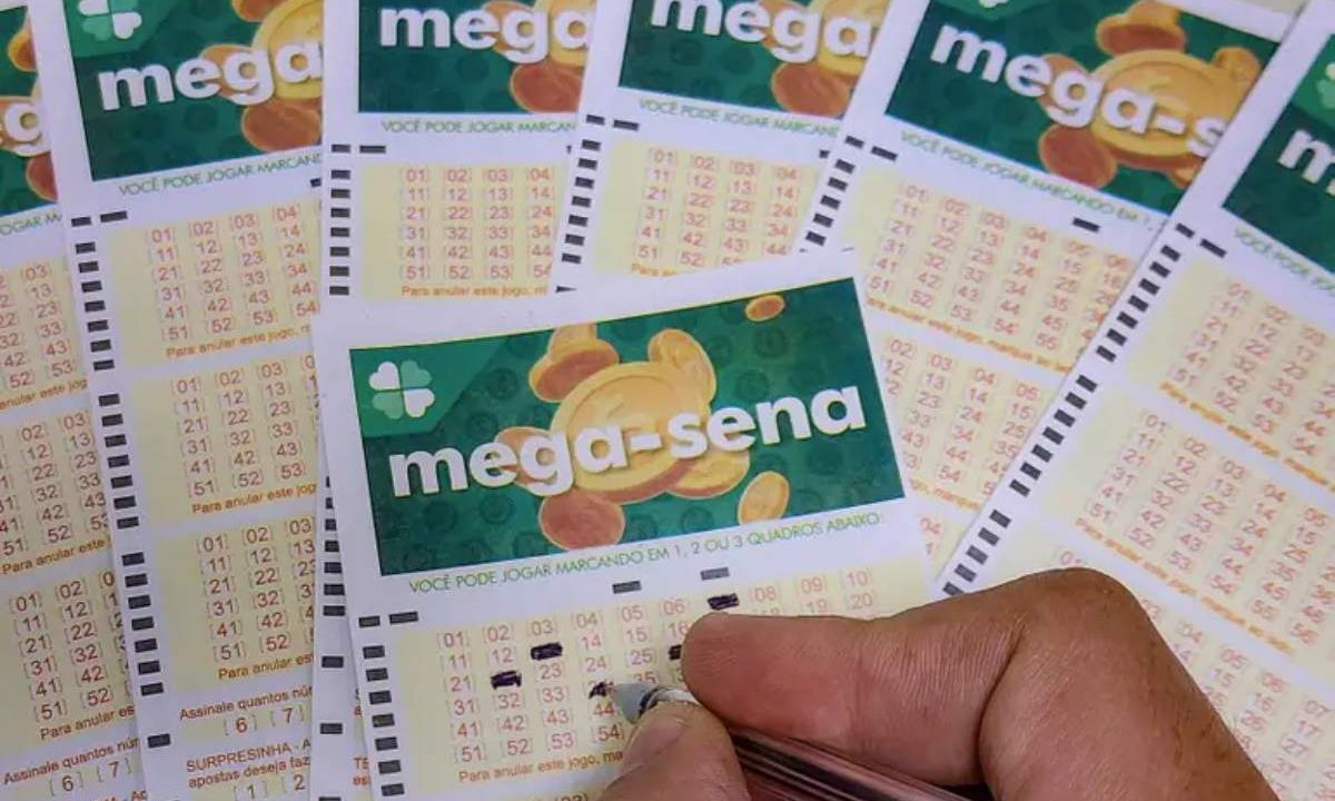Volante da Mega-Sena com pessoa preenchendo os números a caneta