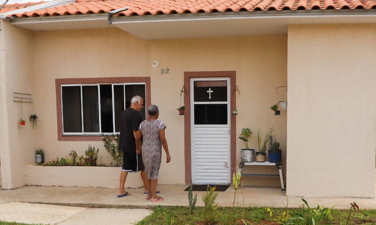 Foto mostra casal de idoso em frente a casa do Minha Casa, Minha Vida