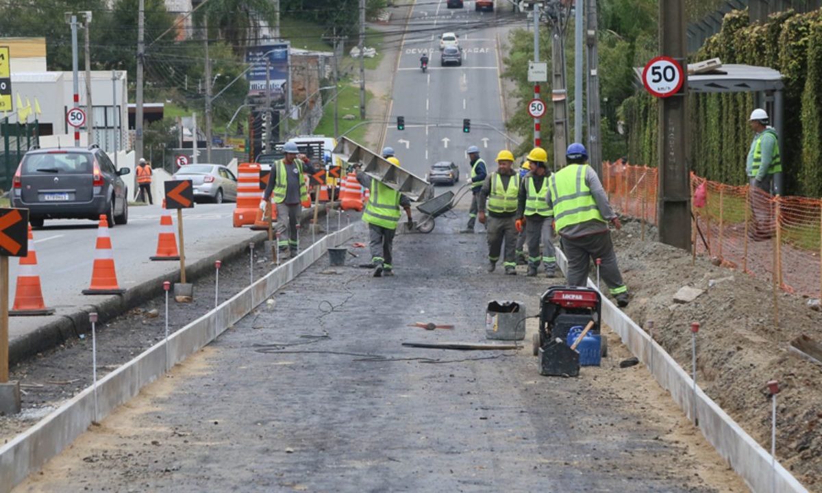 Operários trabalham em obra de revitalização na Rua Major Heitor Guimarães, em Curitiba, enquanto o trânsito segue parcialmente bloqueado.