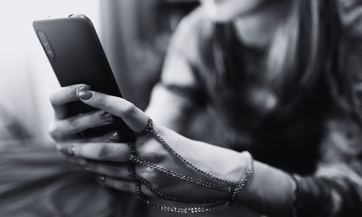 O pai de uma adolescente assumiu o perfil da filha e marcou um encontro com um homem que conversava com ela no Instagram em Umuarama. Foto mostra uma garota no celular. Ela está com pulseira e aneis e segura o celular.