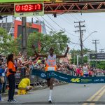 Foto de participantes da Maratona Internacional do Paraná, com um atleta cruzando a linha de chegada.