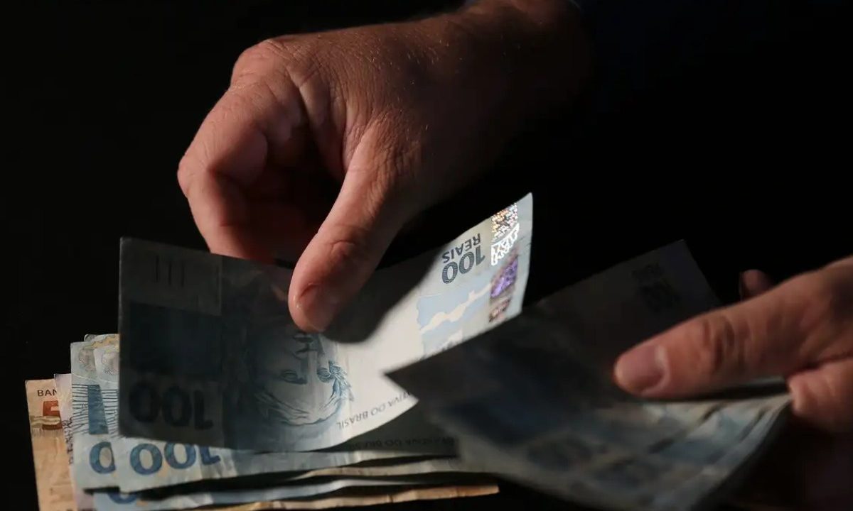 Homem pegando em dinheiro para representar prêmio da Quina 7017