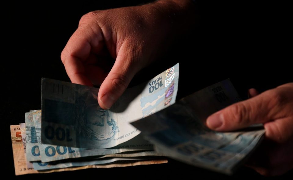 Mão colocando dinheiro na mesa para representar prêmio da Lotomania