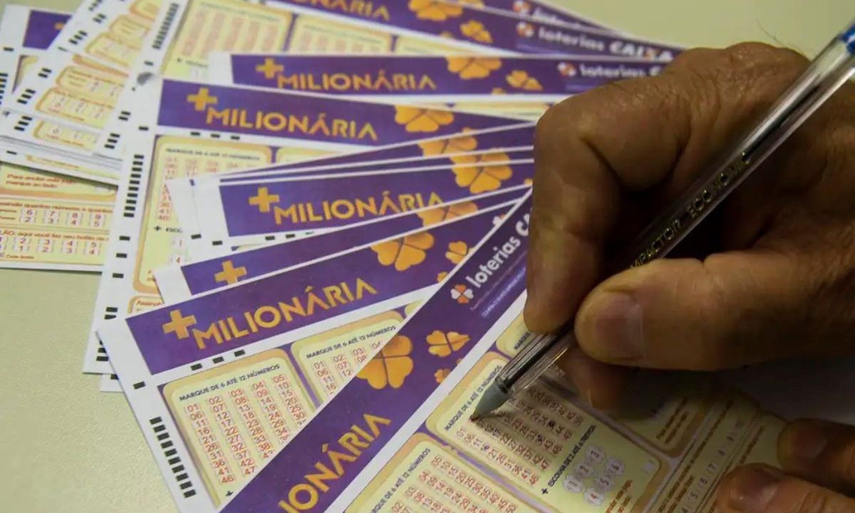 Mão segurando caneta marcando as dezenas no volante da +Milionária 356.