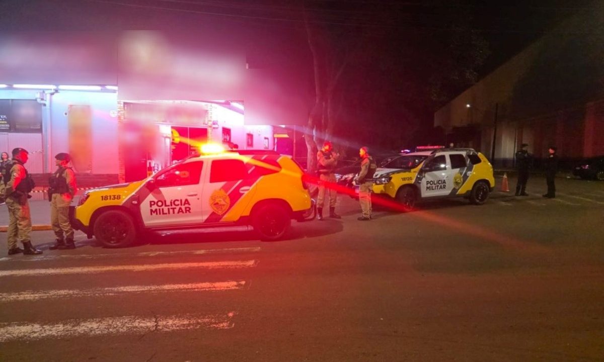 Foto mostra fachada da conveniência onde segurança é suspeito de ter matado homem com tiro na testa. Imagem mostra viaturas da Polícia Militar paradas em frente ao local.