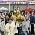 Procissão com altar de flores e fiéis reunidos no pavilhão da festa de Santo Antônio em Cascavel.