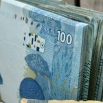 Maço de notas de 100 reais, representando que quem deve terá contas bloqueadas