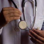 Mãos segurando um estetoscópio, representando um médico médico, que terá aumento no piso salarial, projeto criticado por ministro