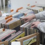 A imagem mostra uma mão mexendo em discos na Feira Nacional Curitiba Vinil