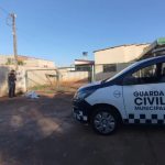 A imagem mostra uma viatura da Guarda Civil Municipal de Maringá estacionada em frente a uma residência durante a manhã de um dia ensolarado. Na calçada, uma mulher aparece deitada e coberta com um material térmico, enquanto permanece imobilizada à espera de atendimento médico. A cena ocorre em uma área residencial e conta com a presença dos guardas que atenderam a ocorrência.
