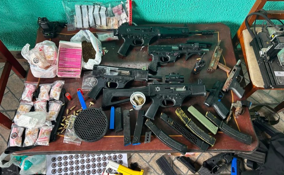 foto mostra o arsenal apreendido em piraquara. suspeito foi preso. foto mostra armas em cima de uma mesa.