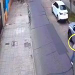 Imagem de câmera de segurança mostra os suspeitos do assalto ao casal de aposentados. Foto mostra uma rua vazia, com dois carros estacionados. Pessoas estão em luta corporal ao canto do lado direito da foto. O idoso usa roupa vermelha.