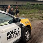 Viatura da Polícia Militar e policiais acompanham os trabalhos no local onde um corpo foi encontrado às margens do Rio Barigui, na Cidade Industrial de Curitiba.