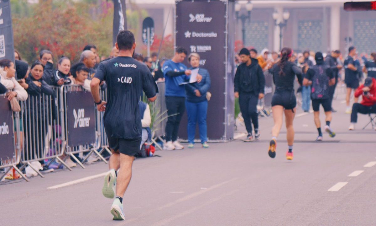 Atletas de costas avançando em reta de chegada de prova de rua em Curitiba, na 15k Run Series Curitiba, evidenciando a postura e o impacto do movimento de corrida na coluna.