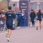 Atletas de costas avançando em reta de chegada de prova de rua em Curitiba, na 15k Run Series Curitiba, evidenciando a postura e o impacto do movimento de corrida na coluna.