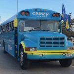 Ônibus escolar azul e amarelo utilizado pela seleção de Curaçao circula pelas ruas durante evento de preparação para a Copa do Mundo de 2026.