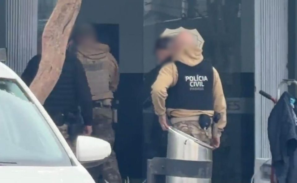 Policiais civis em frente à Central de Flagrantes de Curitiba durante atendimento de ocorrência envolvendo homem baleado após confusão em bar no bairro Hauer.