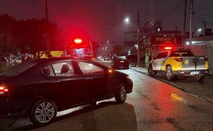 Equipes da polícia e do Siate atendem uma idosa atropelada em rua do bairro Novo Mundo, em Curitiba. Um carro envolvido no acidente permanece parado no local.