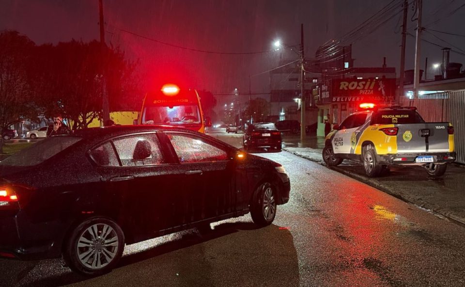 Equipes da polícia e do Siate atendem uma idosa atropelada em rua do bairro Novo Mundo, em Curitiba. Um carro envolvido no acidente permanece parado no local.