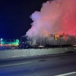 foto mostra uma carreta pegando fogo no contorno leste em curitiba. foto mostra bastante fumaça saindo do veículo. a foto foi feita à noite