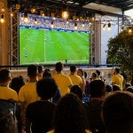 A imagem mostra um telão transmitindo jogos da Copa em Curitiba do Bastards Brewery
