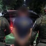 Pai é preso por colocar fogo em casa da ex-companheira no interior do Ceará. Foto mostra o suspeito no meio de dois policiais.