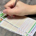 Foto de uma mão preenchendo dois bilhetes de Mega-Sena para o sorteio de hoje.