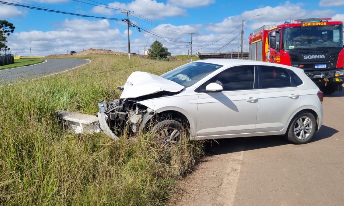Carro branco com a parte da frente destruída depois de bater contra poste em avenida na Cidade Industrial de Curitiba (CIC). A foto também mostra o poste caído.