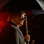 Estados Unidos propõem novas tarifas comerciais que podem atingir exportações brasileiras. A imagem mostra Donald Trump sob um guarda-chuva.