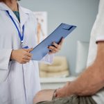 Profissional de saúde conversa com paciente durante consulta médica em consultório em tratamento de câncer de próstata