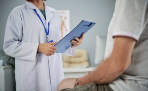 Profissional de saúde conversa com paciente durante consulta médica em consultório em tratamento de câncer de próstata