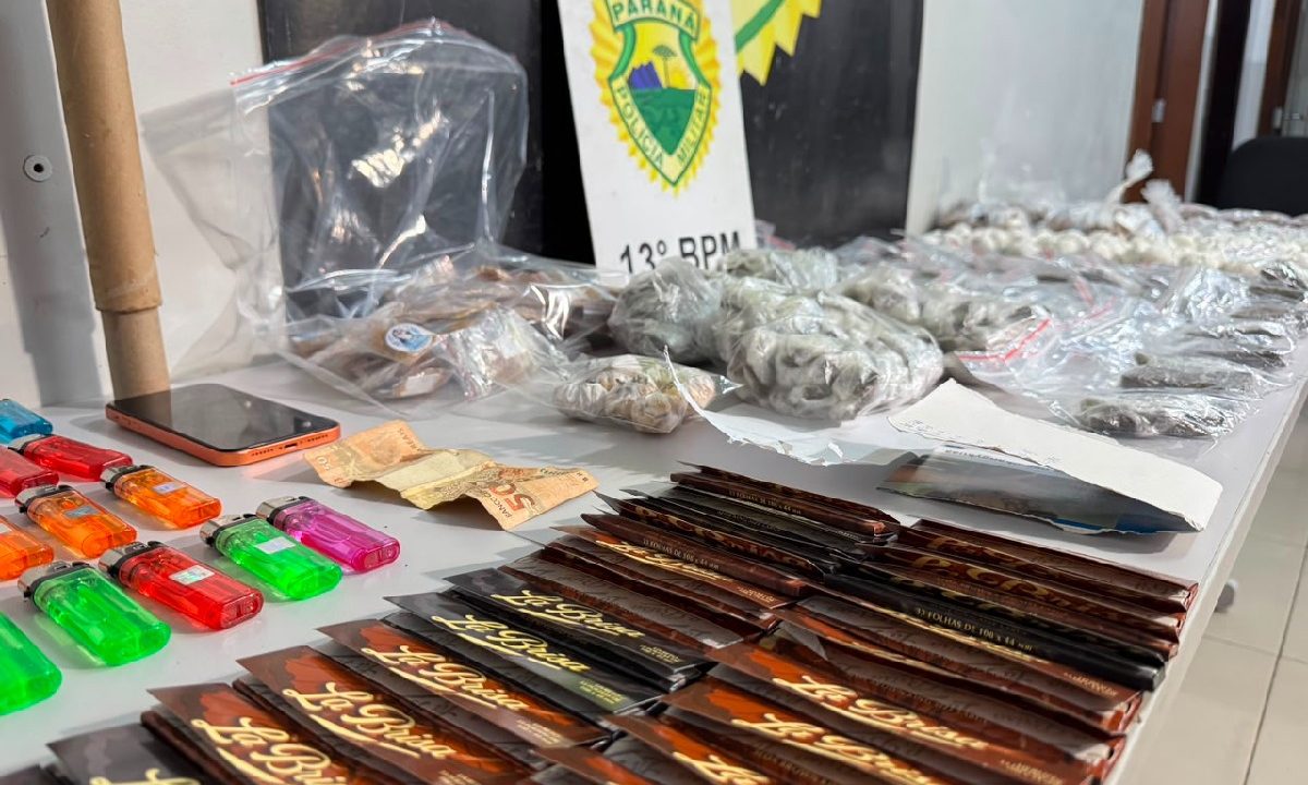Foto mostra mesa com drogas apreendidas com olheiro no Parolin. Na mesa há isqueiros coloridos, sedas e pequenas embalagens com maconha e cocaína. Tudo está alinhado sobre a mesa