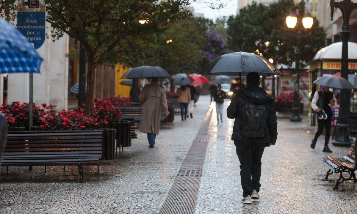 foto ilustrativa para a previsão do tempo em curitiba nesta sexta-feira. foto mostra uma pessoa agasalhada e segurando guarda-chuva