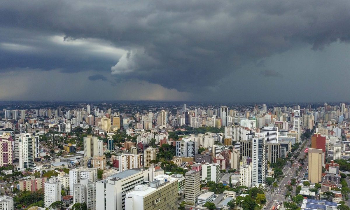 foto ilustrativa para a previsão do tempo em Curitiba nesta quarta-feira. foto mostra curitiba de cima. o céu está fechado e parece que vai chover. a cidade tem muitos prédios e árvores.