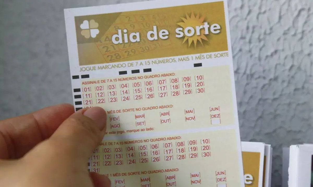 Mão segurando volante do Dia de Sorte 1222.