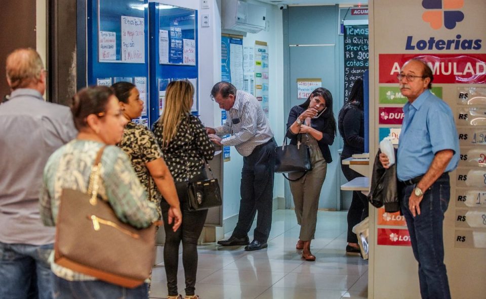 Pessoas em casa lotérica comprando bilhetes da Loteria Federal 6073.