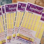 Volantes da Lotofácil sobre notas de R$ 20, R$ 50 e R$ 100.