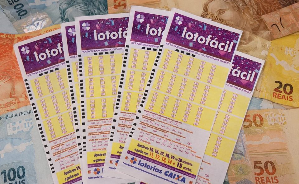 Volantes da Lotofácil sobre notas de R$ 20, R$ 50 e R$ 100.