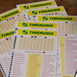 Volantes da Timemania 2400 sobre mesa de madeira.