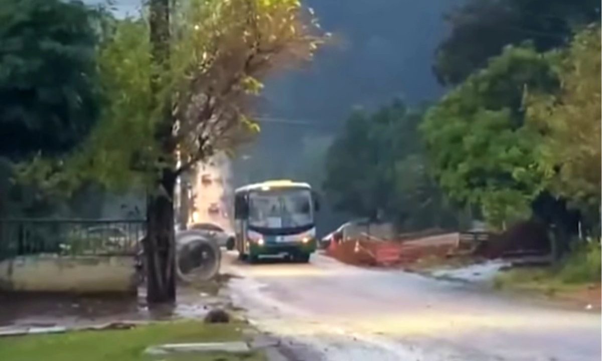 Ônibus está parado no meio de uma rua com subida.