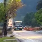 Ônibus está parado no meio de uma rua com subida.