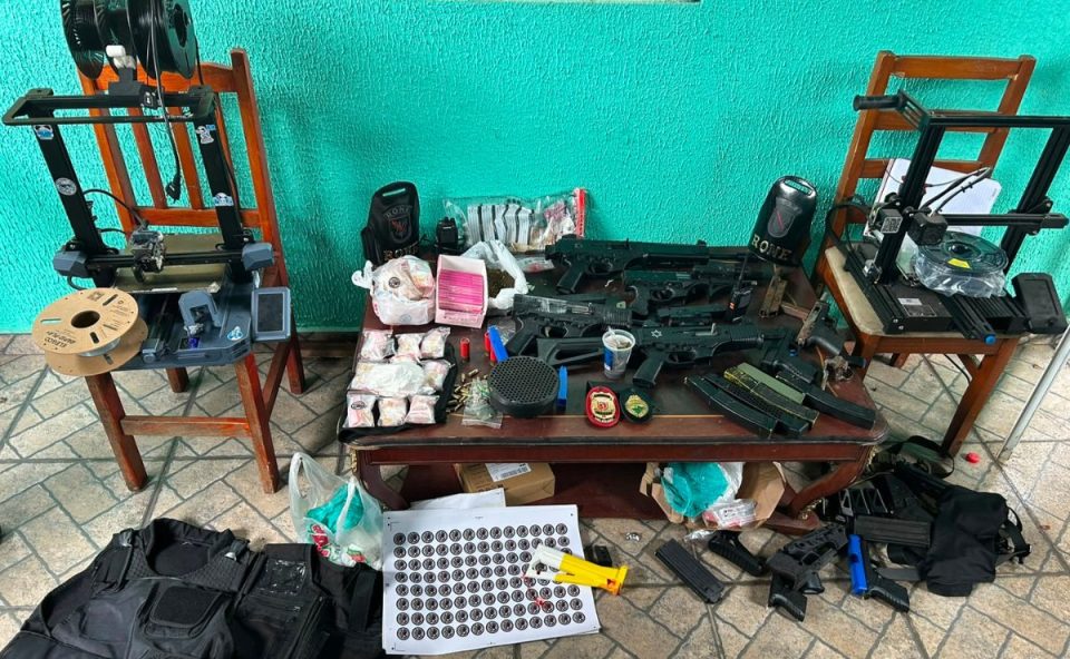 foto mostra o arsenal apreendido em piraquara. suspeito foi preso. foto mostra armas em cima de uma mesa.