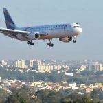 Avião da Latam Airlines sobrevoando uma área urbana durante o dia, ilustrando matéria sobre a redução no preço do combustível pela Petrobras querosene aviação.